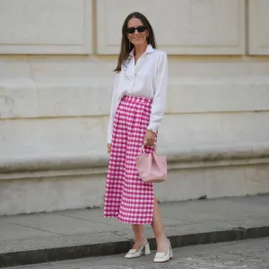 Alba Garavito Torre wears black sunglasses from Ray Ban, white pearl and gold chain pendant earrings, a transparent large pearls long necklace, a white shirt, pink and white checkered print pattern midi pants from Frambuã, gold bracelets, a pale pink matte leather handbag from Saonara Brand, white latte matte shiny leather block heels mules from Jonak, during a street style fashion photo session, on June 06, 2023 in Paris, France.