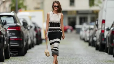 Segolene Hyppolite wears sunglasses, a sleeveless black and white embroidered wool midi dress from Vanessa Bruno, a beige raffia bag from Vanessa Bruno, a Chanel Premiere watch, a Nach bracelet, Chanel sandals / shoes, during a street style fashion photo session, on May 20, 2024 in Paris, France.