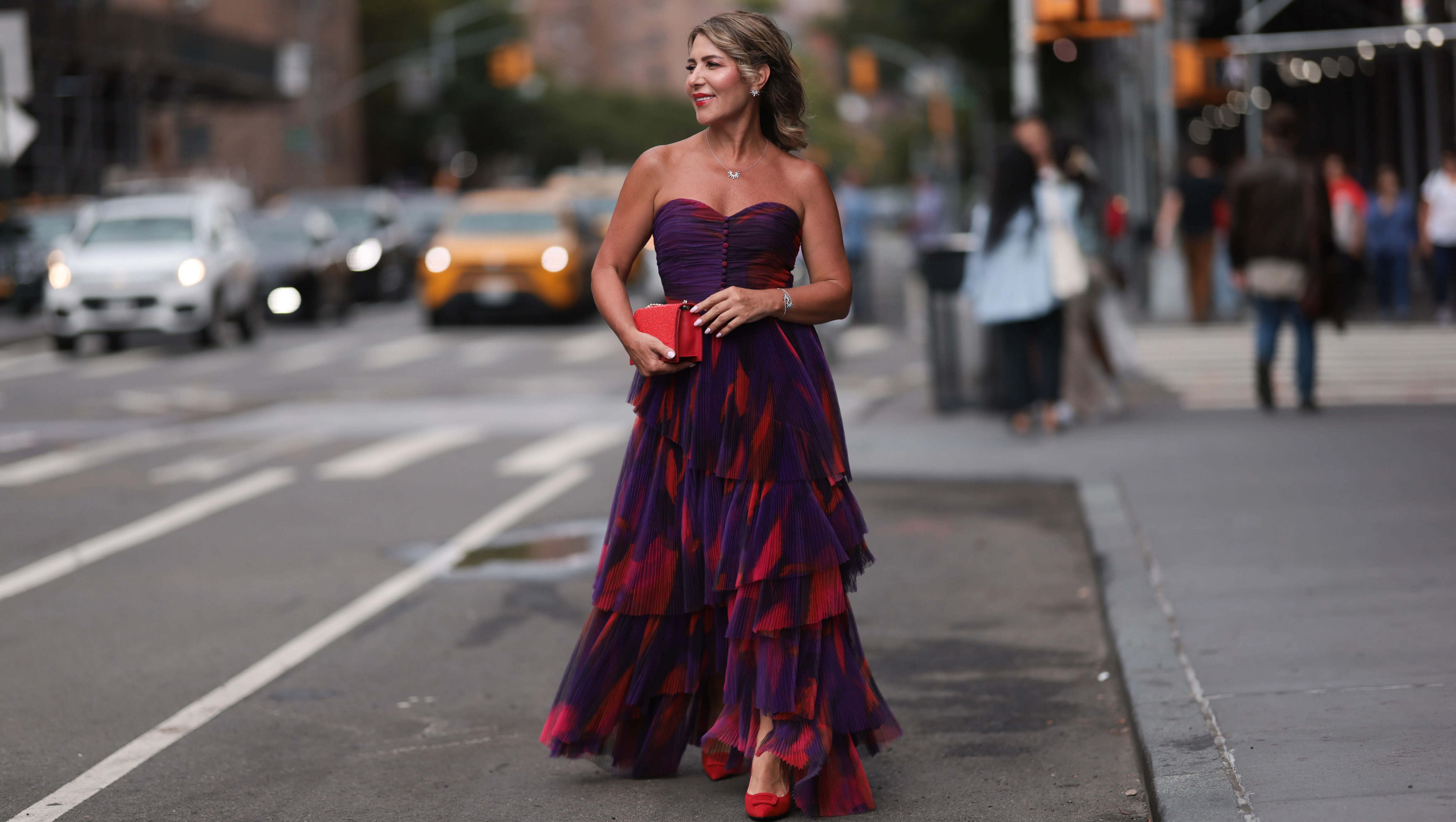NEW YORK, NEW YORK - SEPTEMBER 07: Olga Ferrara seen wearing Leibish diamond necklace / diamond earrings / diamond bracelet, Hutch pink / purple pattern bandeau pleated long dress, Emanuel Ungaro red leather clutch bag and Scarlett Chase red suede leather pumps / heels, on September 07, 2024 in New York City. (Photo by Jeremy Moeller/Getty Images)