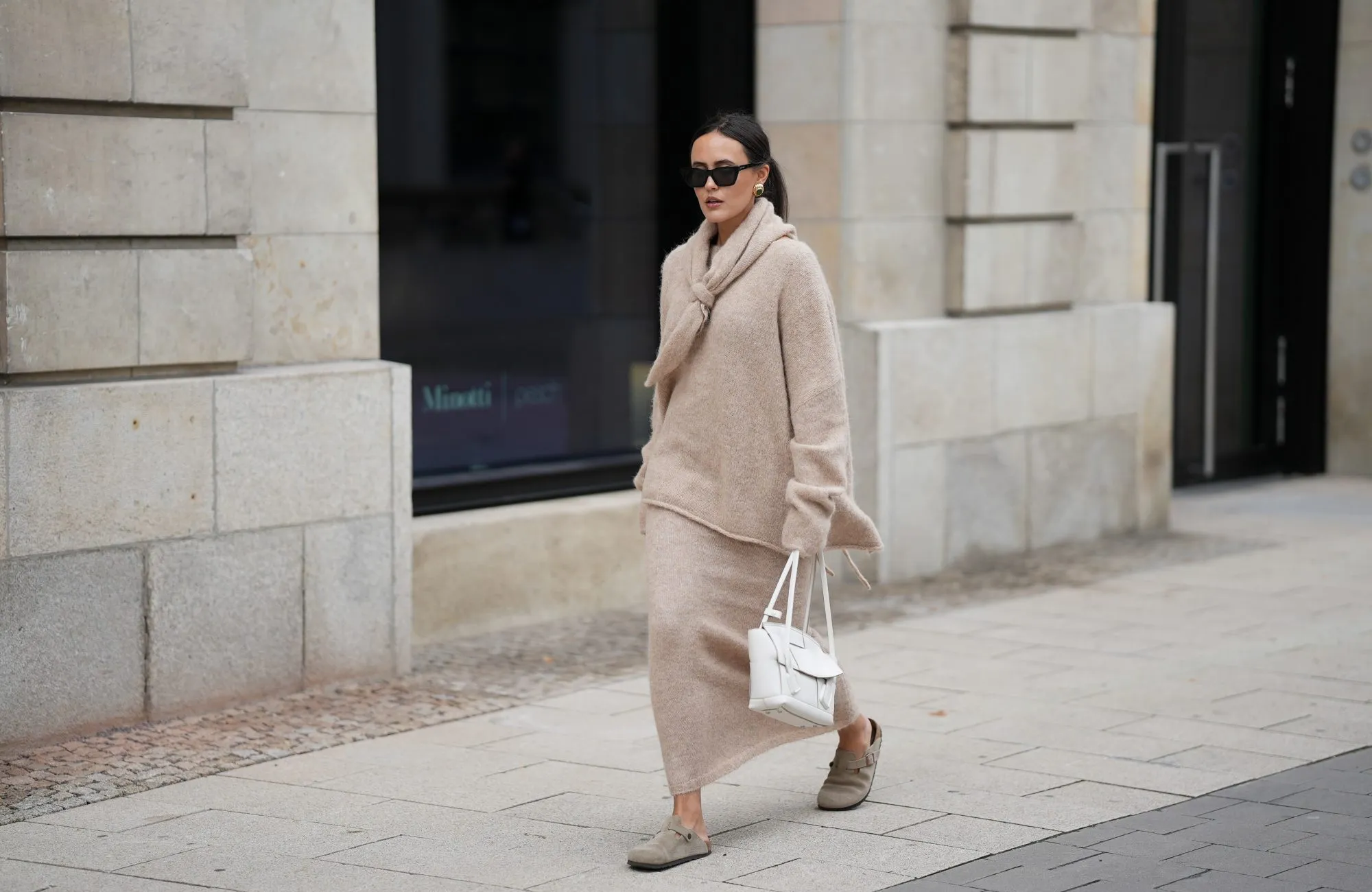 HAMBURG, GERMANY - OCTOBER 16: Laura Noltemeyer is seen wearing an oversized beige alpaca wool sweater with tie-back detailing by Aylin König; a long alpaca wool knit skirt in a straight cut by Aylin König; an alpaca knit scarf draped and knotted around the neck by Aylin König; beige suede Boston clogs by Birkenstock; a white intrecciato leather handbag called „Arco Bag“ by Bottega Veneta; slim black cat-eye sunglasses by Yves Saint Laurent; gold statement earrings with a green stone detail by Mango; her brown and straight hair is tied in a low ponytail on October 16, 2025 in Hamburg, Germany. (Photo by Moritz Scholz/Getty Images)