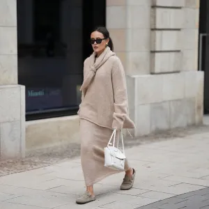 HAMBURG, GERMANY - OCTOBER 16: Laura Noltemeyer is seen wearing an oversized beige alpaca wool sweater with tie-back detailing by Aylin König; a long alpaca wool knit skirt in a straight cut by Aylin König; an alpaca knit scarf draped and knotted around the neck by Aylin König; beige suede Boston clogs by Birkenstock; a white intrecciato leather handbag called „Arco Bag“ by Bottega Veneta; slim black cat-eye sunglasses by Yves Saint Laurent; gold statement earrings with a green stone detail by Mango; her brown and straight hair is tied in a low ponytail on October 16, 2025 in Hamburg, Germany. (Photo by Moritz Scholz/Getty Images)