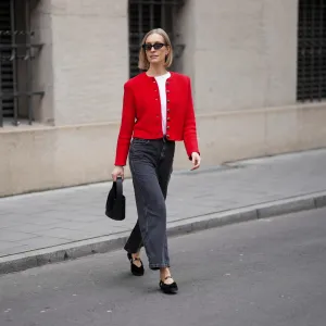 MUNICH, GERMANY - MARCH 27: Marlies Pia Pfeifhofer is seen wearing a red knit "Janker" cardigan featuring decorative silver buttons from La Foresta; a white cotton short sleeve T-shirt with padded shoulders from The Attico; dark grey cropped denim jeans with a straight leg from Sézane; black velvet pointed toe ballet flats with a crossover Mary Jane strap and gold tone charm hardware detailing from La Foresta x Flabelus; a black leather "Gunther" mini bag with a compact structured silhouette and a tonal circular passementerie disc detail from Destree; small black acetate cat eye sunglasses with dark lenses called "Blum" from Kaleos; delicate gold "Eva" hoop earrings from Sézane; her blonde hair is styled in a straight chin length bob with a center part on March 27, 2026 in Munich, Germany. (Photo by Moritz Scholz/Getty Images)