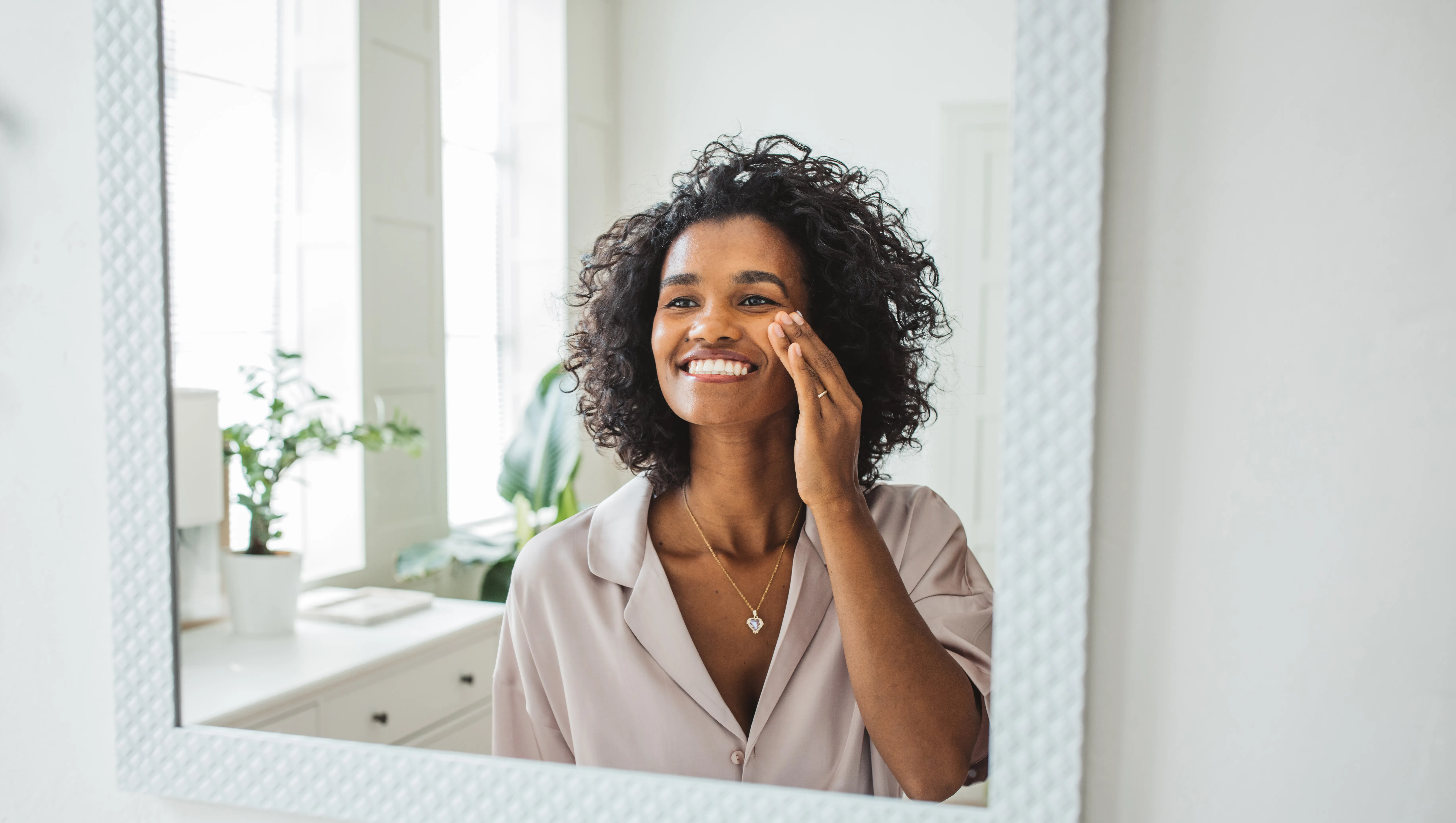 Attractive young woman cleaning her face with a cotton pad in the bathroom at home
