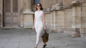 PARIS, FRANCE - MAY 25: Marissa Cox wears a white Arket linen skirt set, a sleeveless long top with buttons, a brown raffia Loewe basket bag, ATP Atelier brown suede sandals / shoes, Jimmy Fairly x Reformation sunglasses, during a street style fashion photo session, on May 25, 2024 in Paris, France. (Photo by Edward Berthelot/Getty Images)