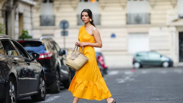 PARIS, FRANCE - AUGUST 12: Ketevan Giorgadze @katie.one wears a one shoulder cut out maxi dress in orange from Mango, oversized golden hoop earrings from Zara, flip flop heeled black sandals shoes from APC Paris, a Le Grand Panier beach straw bag by Jacquemus, on August 12, 2021 in Paris, France. (Photo by Edward Berthelot/Getty Images)