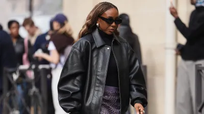 PARIS, FRANCE - MARCH 07: A guest wears brown braided hair, black sunglasses, a black leather oversized bomber jacket, a black knit turtleneck top, a purple leather pencil skirt with silver metal grommets, black varnished leather pointed pumps heels shoes, outside Celine, during Paris Fashion Week - Womenswear Fall/Winter 2026/2027, on March 07, 2026 in Paris, France (Photo by Edward Berthelot/Getty Images)