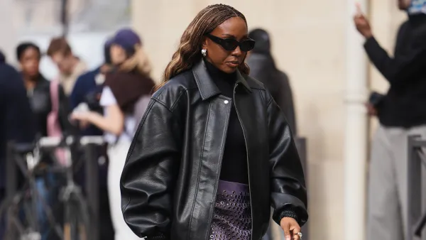 PARIS, FRANCE - MARCH 07: A guest wears brown braided hair, black sunglasses, a black leather oversized bomber jacket, a black knit turtleneck top, a purple leather pencil skirt with silver metal grommets, black varnished leather pointed pumps heels shoes, outside Celine, during Paris Fashion Week - Womenswear Fall/Winter 2026/2027, on March 07, 2026 in Paris, France (Photo by Edward Berthelot/Getty Images)