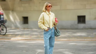 FRANKFURT AM MAIN, GERMANY - APRIL 21: Julia Kammerer is seen wearing a yellow pinstripe button down shirt tucked into the pants from Pacific Republic; a yellow and blue pinstripe tie from Pull&Bear; light wash straight leg jeans from Replay; brown leather "Speedboat" lace-up sneakers from Puma; a blue and beige "Gucci Denim GG Monogram Sukey Tote Bag" with tan leather trim and gold tone hardware from Gucci; orange tinted oversized shield sunglasses with a bold orange frame from & Other Stories; a pale pink manicure; holding a red Coca Cola can; several chunky jewelry pieces in gold and silver including rings and hoop earrings from Pandora, Akind, & other stories, H&M, my jewellery or scandiv; her blonde hair is styled in a straight long bob; with a natural make up look on April 21, 2026 in Frankfurt am Main, Germany. (Photo by Moritz Scholz/Getty Images)