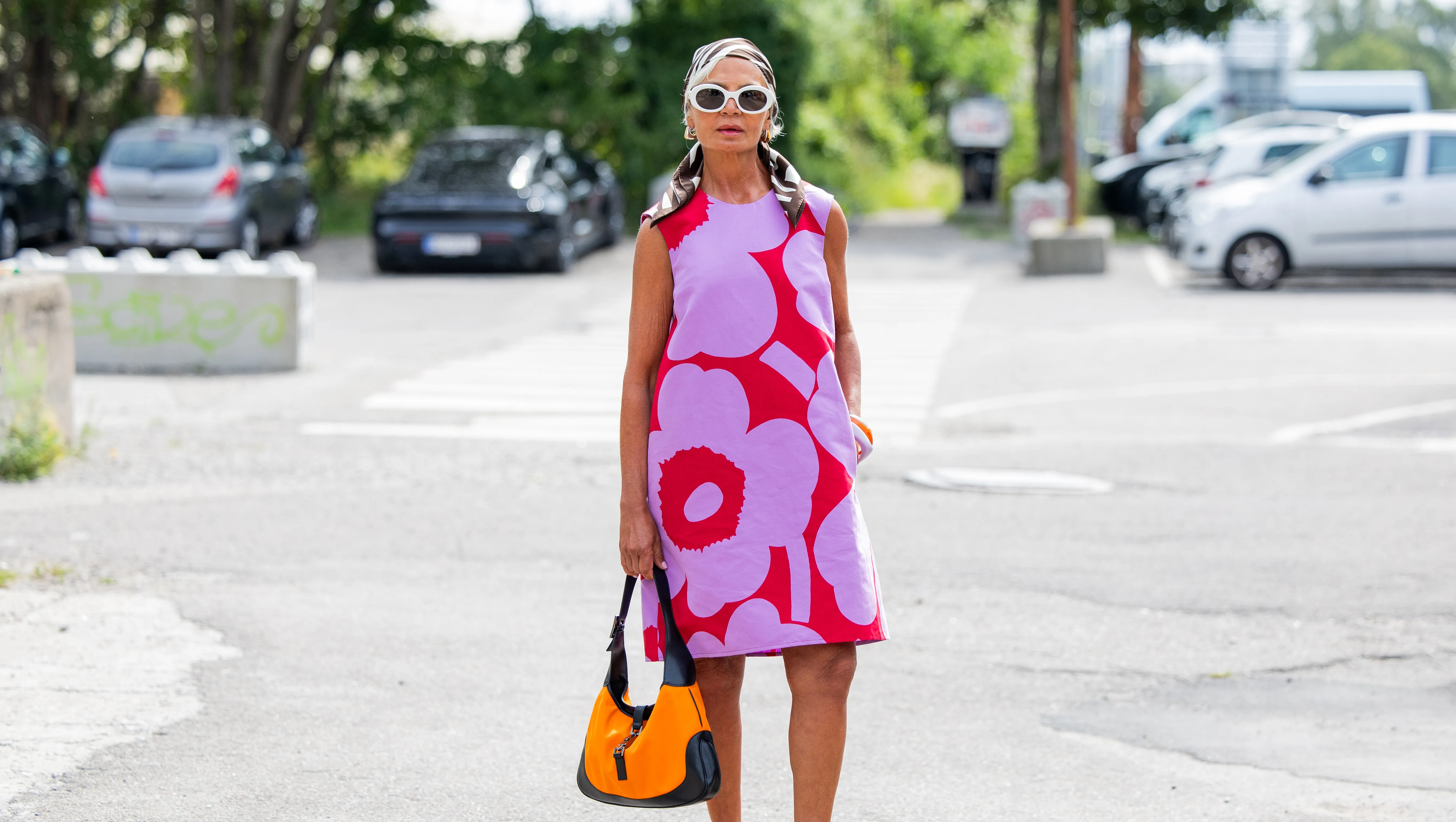 COPENHAGEN, DENMARK - AUGUST 07: Grece Ghanem wears sleeveless pink red dress, head scarf, white sunglasses, orange black bag outside Marimekko during Copenhagen Fashion Week day four on August 07, 2025 in Copenhagen, Denmark. (Photo by Christian Vierig/Getty Images)