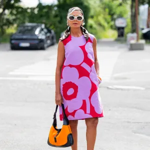 COPENHAGEN, DENMARK - AUGUST 07: Grece Ghanem wears sleeveless pink red dress, head scarf, white sunglasses, orange black bag outside Marimekko during Copenhagen Fashion Week day four on August 07, 2025 in Copenhagen, Denmark. (Photo by Christian Vierig/Getty Images)