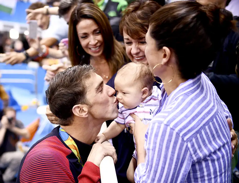 USA's Michael Phelps kisses his son, Boomer, next to his fianc&eacute;e, Nicole Johnson (R) and mother Deborah (C) after he won the men's 200-meter butterfly final at the Rio 2016 Olympic Games at the Olympic Aquatics Stadium in Rio de Janeiro on August 9, 2016.