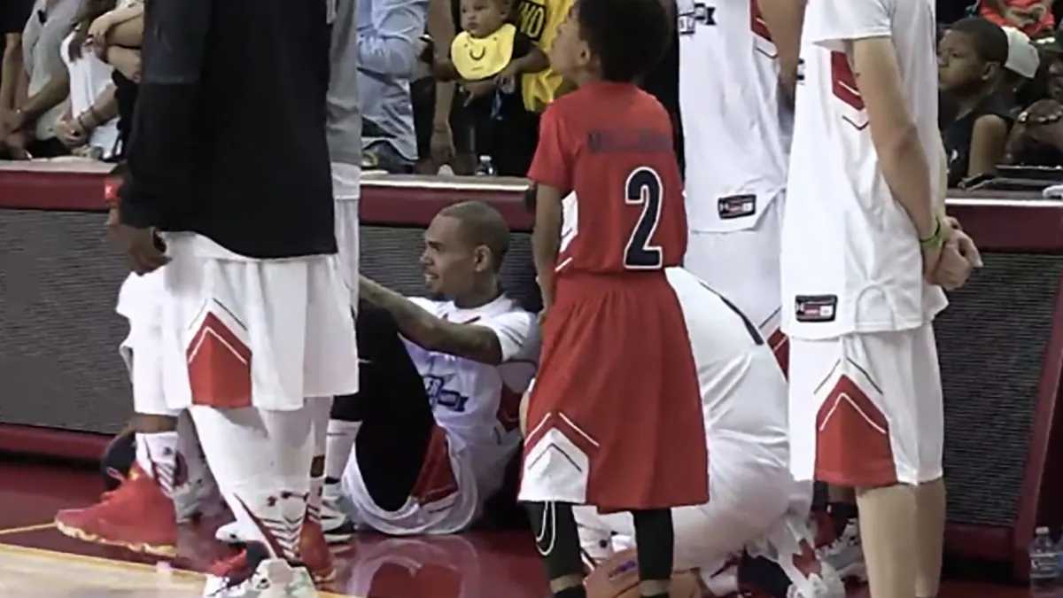 Chris Brown sits during the national anthem