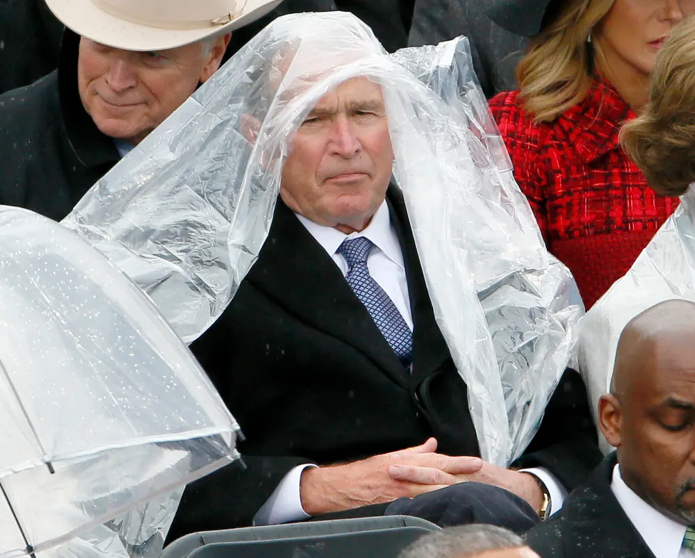 Former President George W. Bush keeps covered under the rain during the inauguration ceremonies swearing in Donald Trump as the 45th president of the United States on the West front of the U.S. Capitol in Washington, U.S., January 20, 2017.
