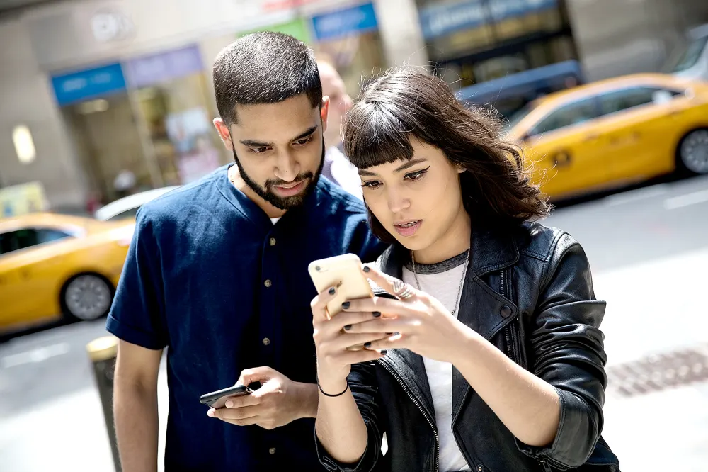 Sameer Uddin and Michelle Macias play Pok&eacute;mon Go on their smartphones outside of Nintendo's flagship store, July 11, 2016 in New York City.