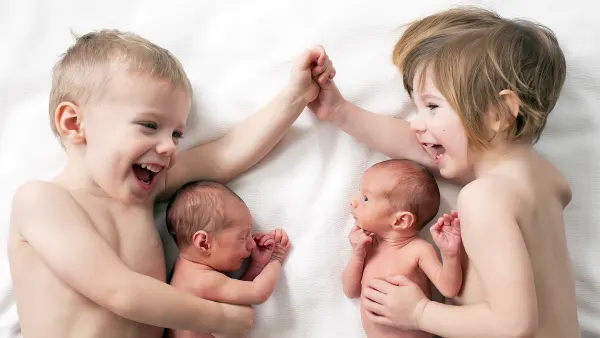 Toddler Twins Cuddling Their Newborn Twin Siblings